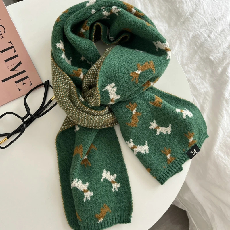 Green knitted scarf with Scottie dog pattern on a white surface