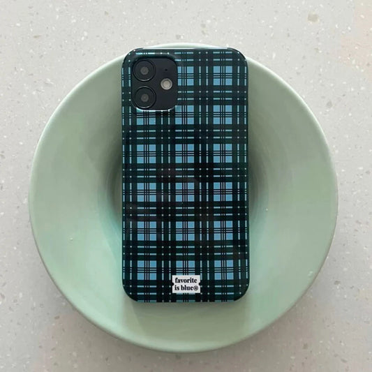 A smartphone case with a blue and black plaid pattern, shown on a phone resting inside a light green ceramic bowl on a speckled countertop. The brand name 'favorite is blue co.