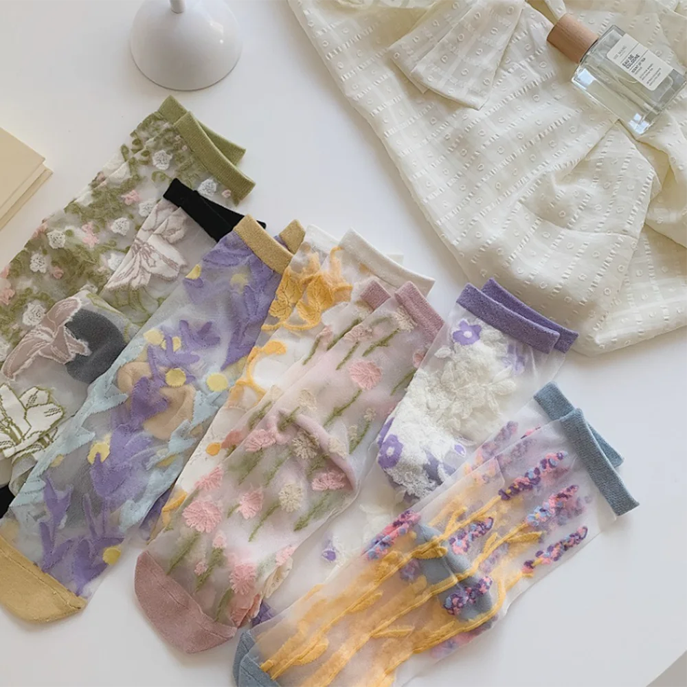 Set of floral-patterned sheer socks on a white surface with a white garment and bottle in the background.