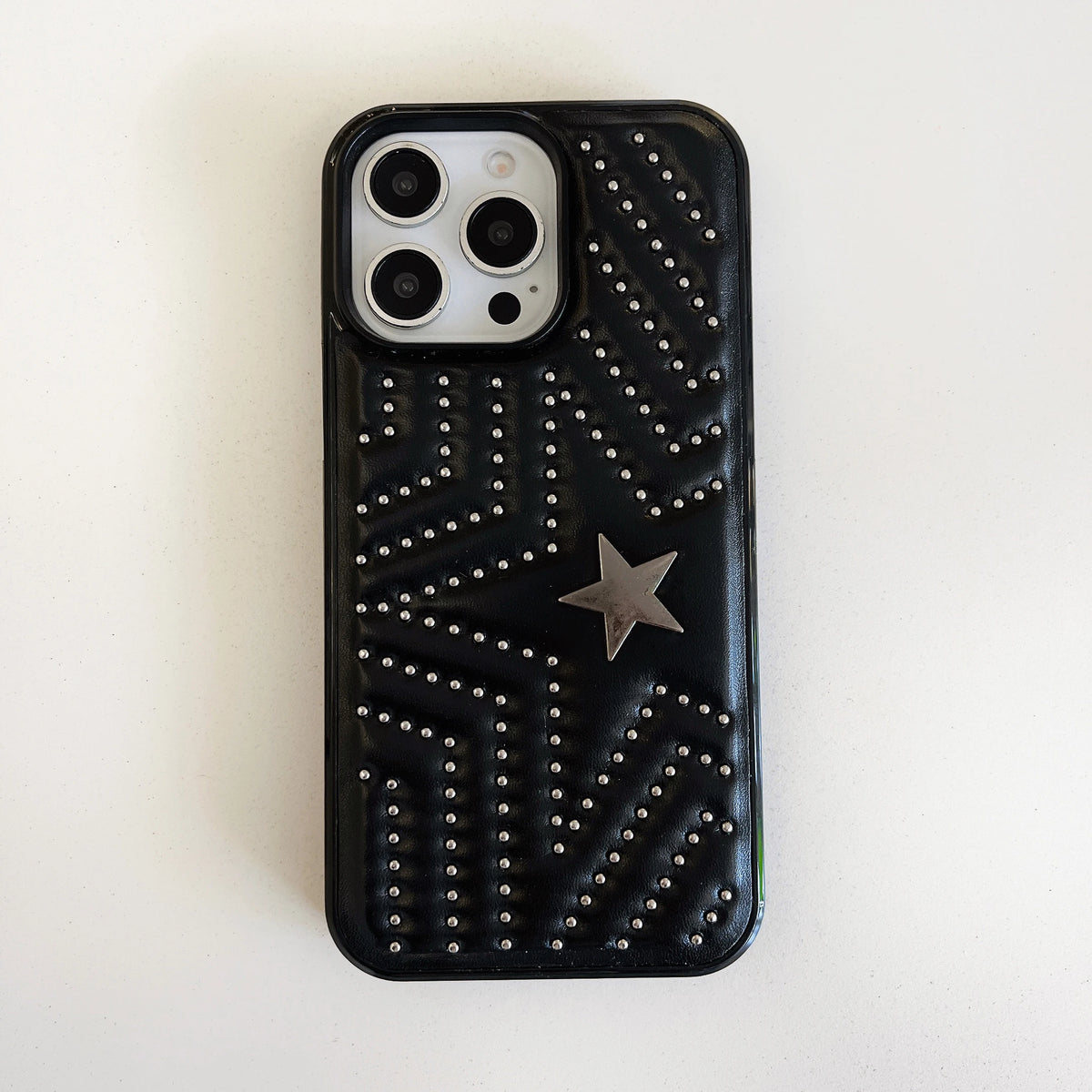 A black protective phone case for an iPhone, decorated with silver rhinestones in a geometric pattern and a central silver star, shown on a plain off-white background.