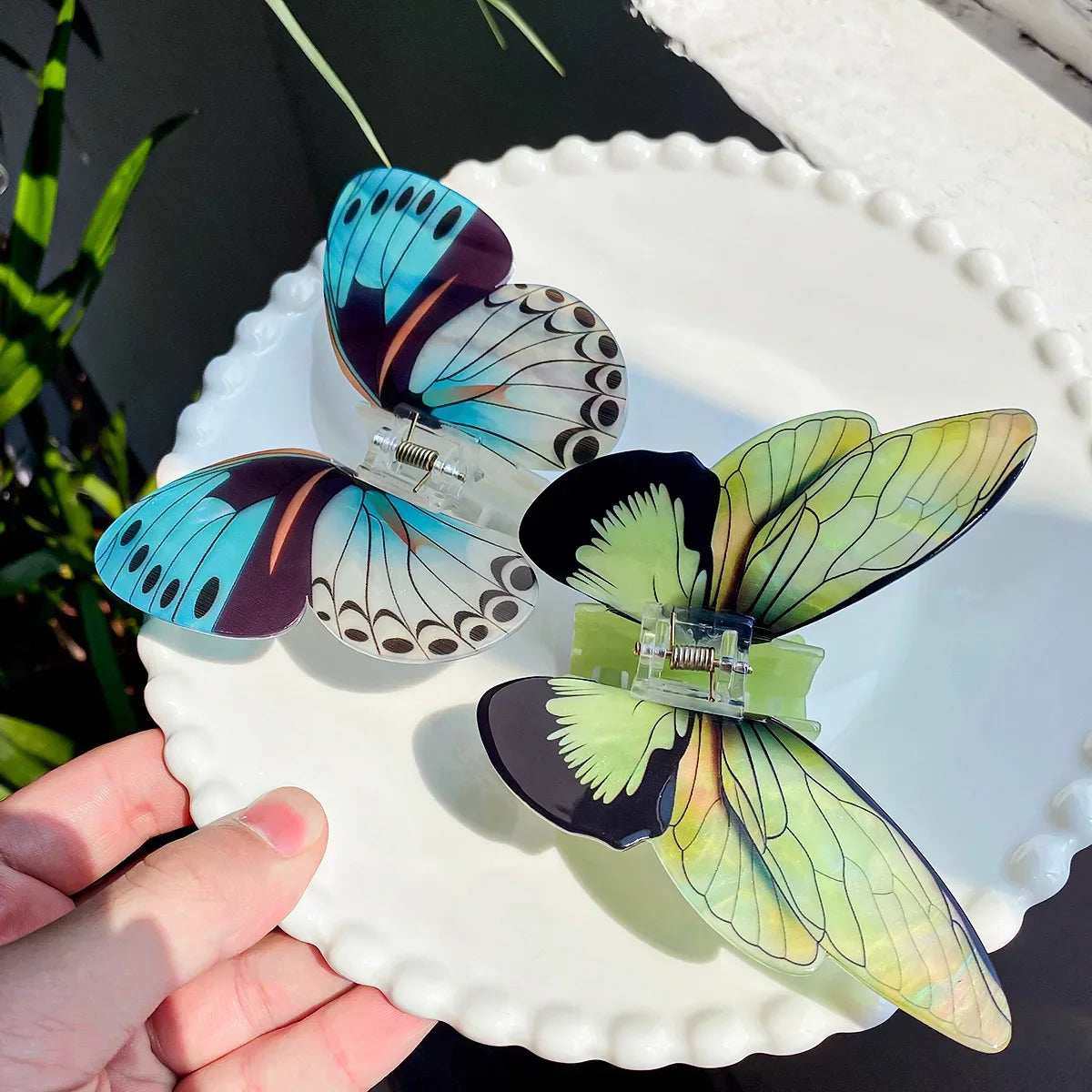 Butterfly-shaped hair clips on a decorative plate held by a hand.