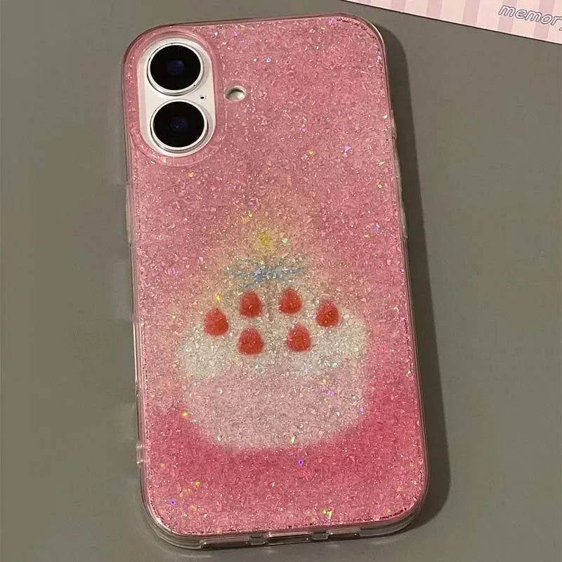 A pink glittery phone case with a printed cake design featuring red cherries, shown on a smartphone against a gray background.