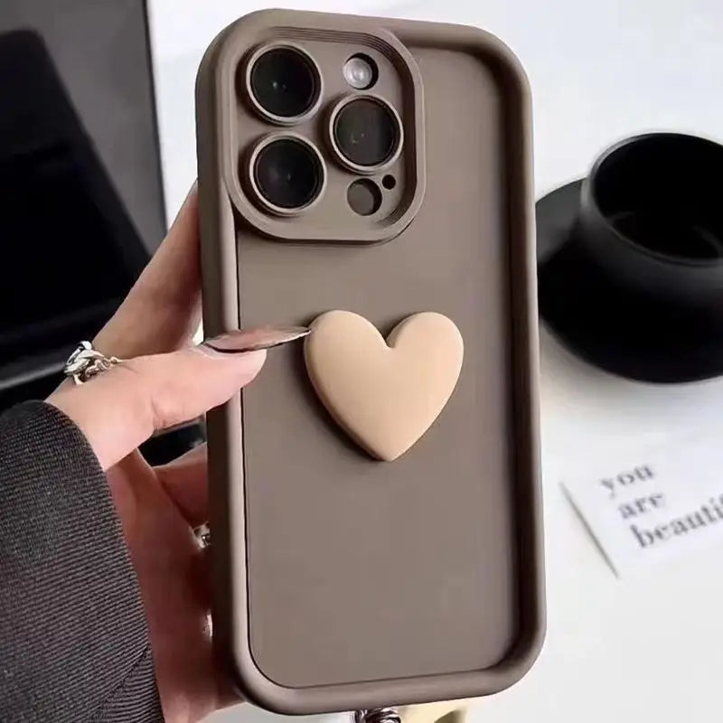 Phone case with heart design held by a hand, with a cup and text in the background