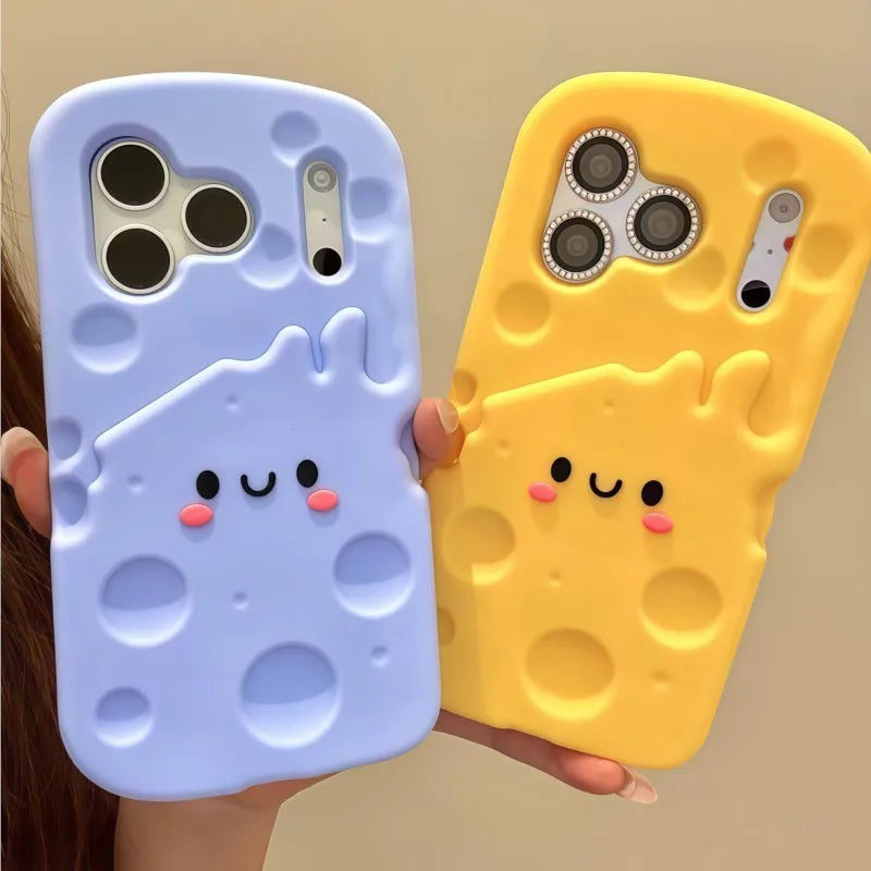 Two 3D cheese-shaped phone cases, one light blue and one yellow, held in hands against a plain beige background. The cases feature a cute cartoon face with black eyes, a smiling mouth, and pink cheeks, with the cheese holes detailed in the back.