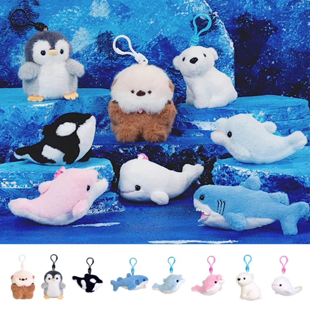 A set of plush animal keychains displayed on a blue icy background, including penguins, seals, an orca, whales, a shark, and a pink dolphin. A row of smaller keychain previews appears along the bottom.