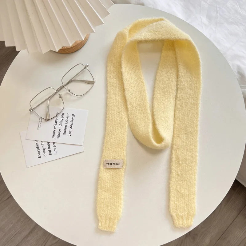 Yellow knitted scarf on a white surface with glasses and papers.