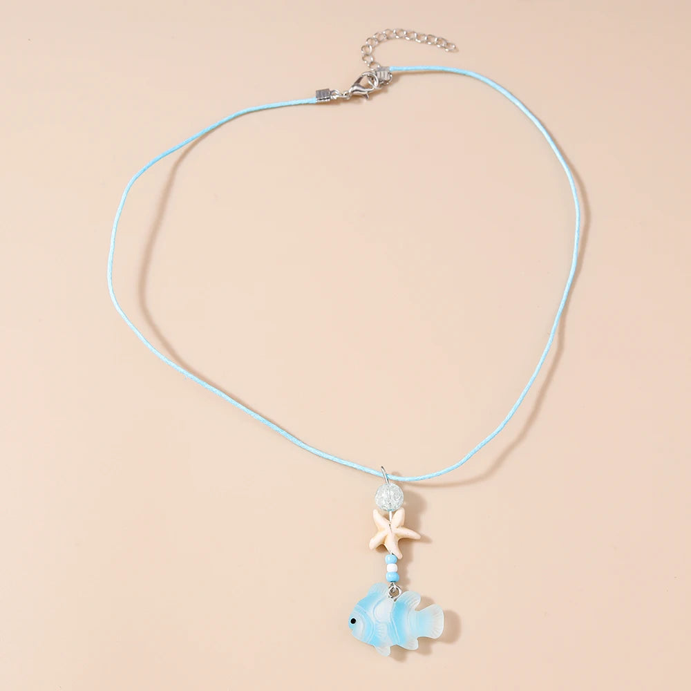 Necklace with a fish and starfish pendant on a beige background