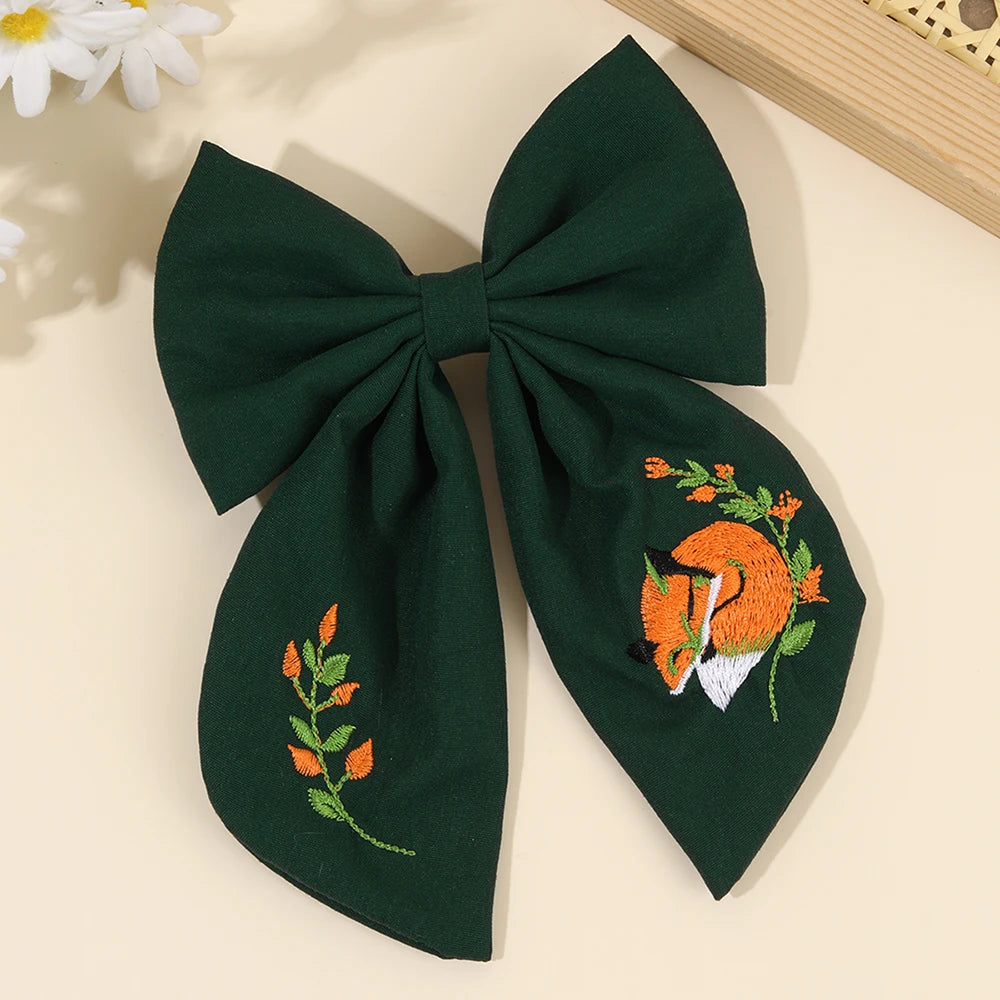 Green bow with embroidered fox design on a light background