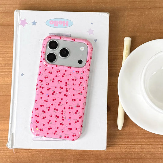 Pink phone case with cherry pattern on a white box with 'Hello' branding, on a wooden surface.