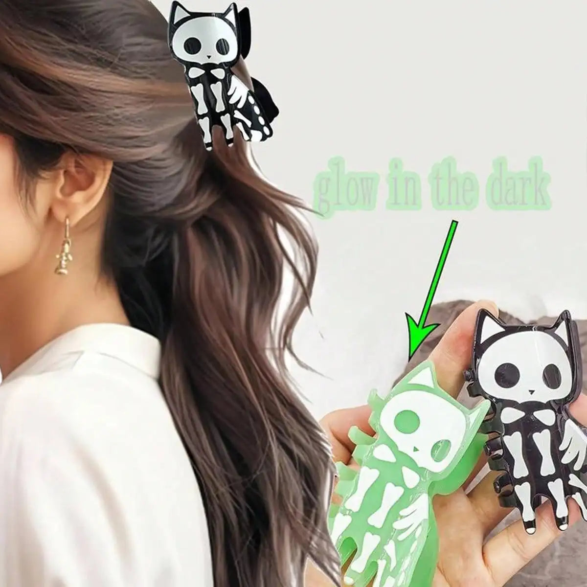 A person wearing a black-and-white cat skeleton hair clip, with the product shown again in hand alongside a green glow-in-the-dark text overlay and arrow. The clip has a cartoon cat skeleton design with wings.