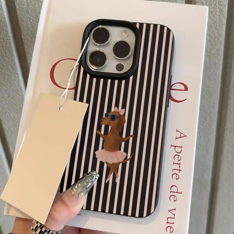 A phone case with a black and white vertical stripe pattern and a cartoon dog in a pink tutu, held over a white book by a hand with silver nail art.