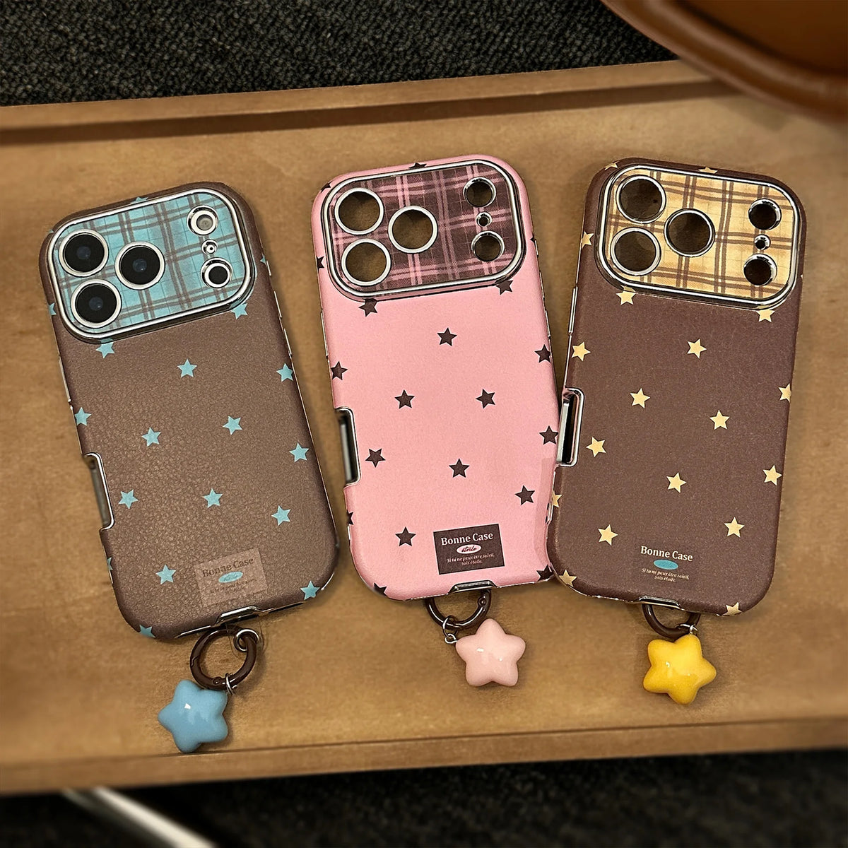 Three phone cases with star charms on a brown surface