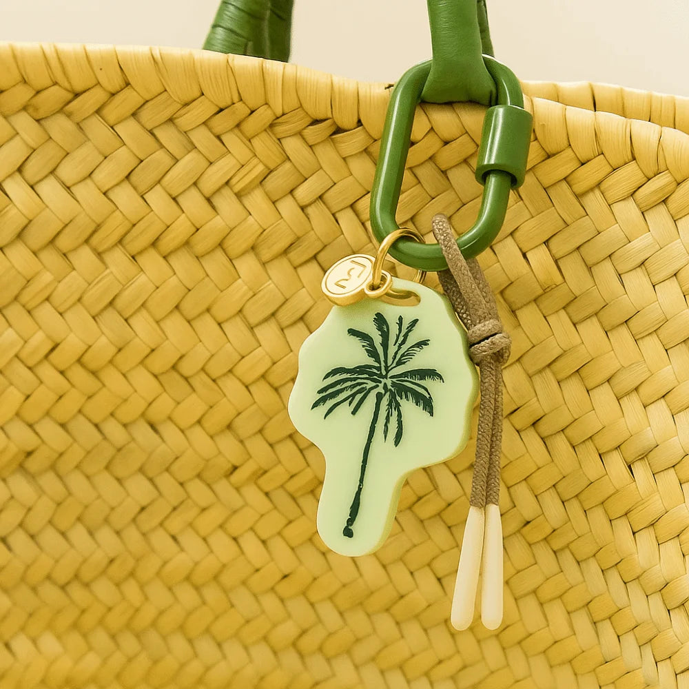 Woven bag with a palm tree keychain on a neutral background