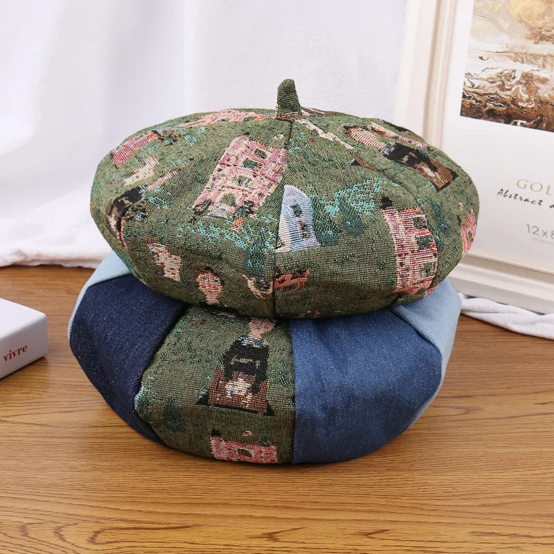 A round beret with a patchwork design, featuring a green woven patterned fabric on the top half and solid blue fabric on the bottom half, placed on a wooden table.