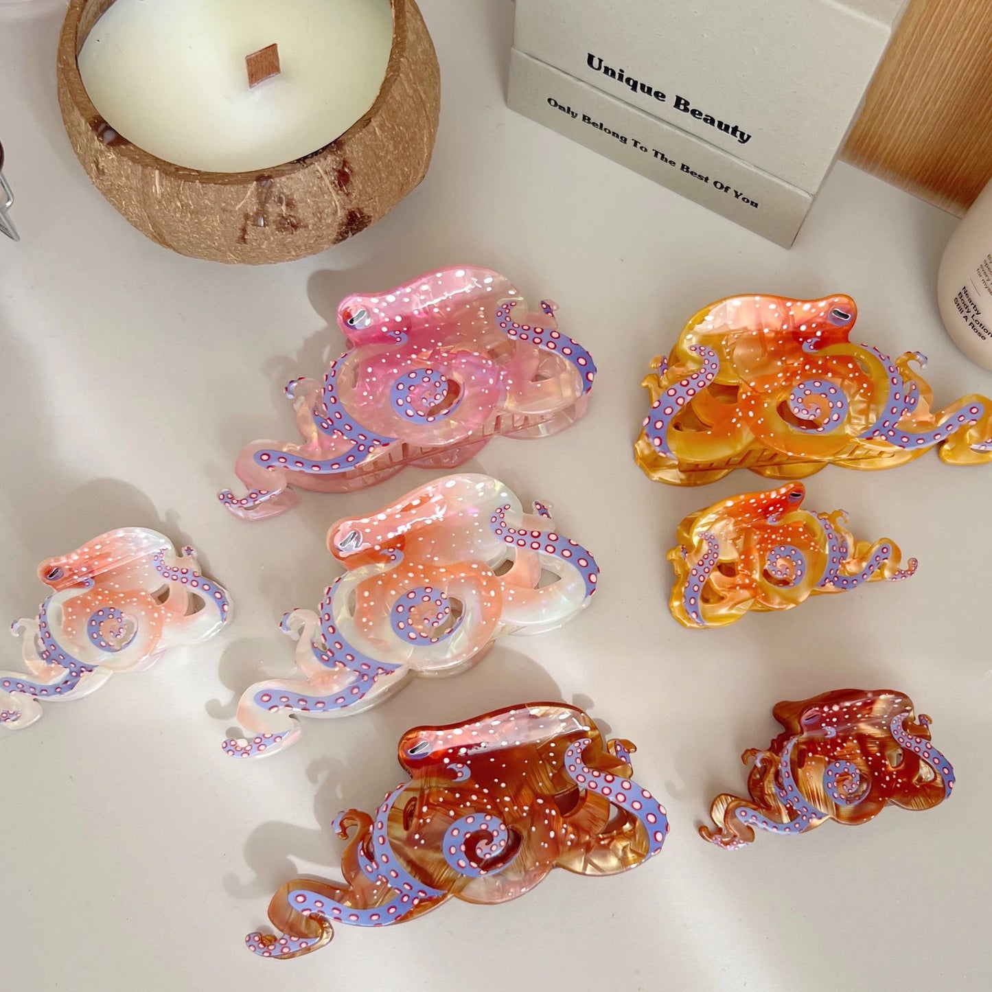 Colorful octopus-shaped hair claws on a white surface with a coconut container and box in the background.