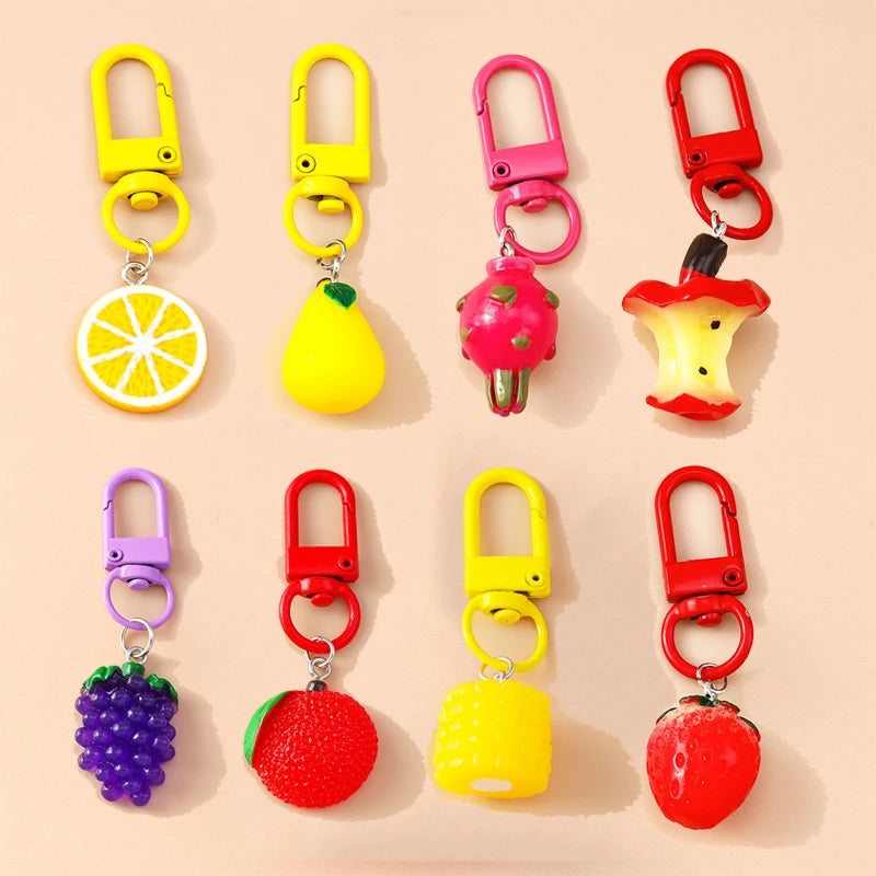 Colorful fruit-shaped keychains on a beige background