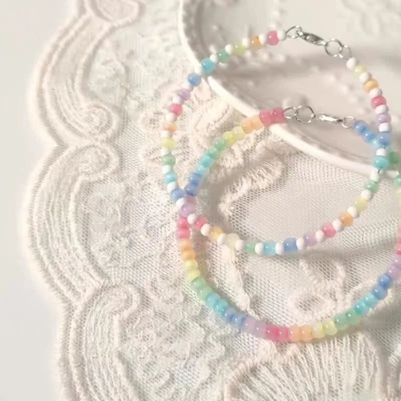 Pastel beaded necklace and bracelet on a textured white surface