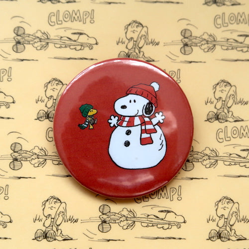 A vintage style pin button badge featuring Snoopy the beagle from the Peanuts comics dressed as a snowman Woodstock