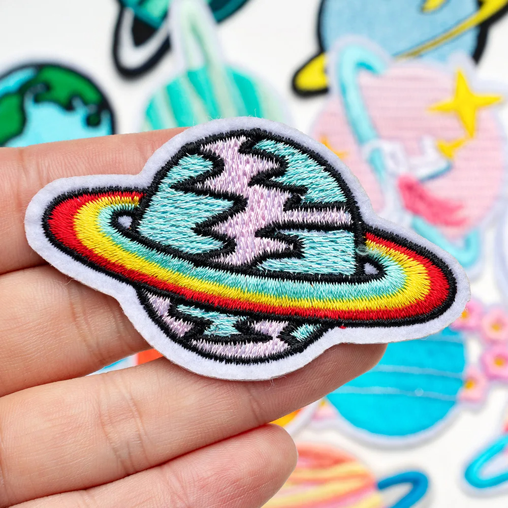 Colorful embroidered patch of a cartoon character with a rainbow on a hand, with more patches in the background.