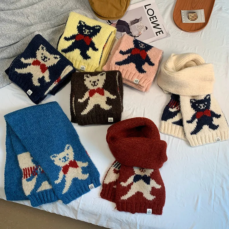 Collection of colorful knitted scarves with animal patterns on a bed.