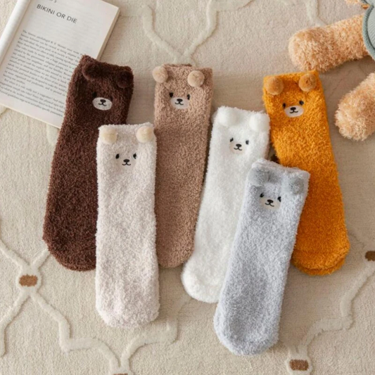 A collection of fuzzy ankle socks in various colors, each featuring an embroidered teddy bear face and pom pom ears.