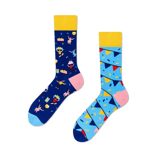 A pair of mismatched crew socks, one with a bunting design and the other featuring a party scene with cake and presents.