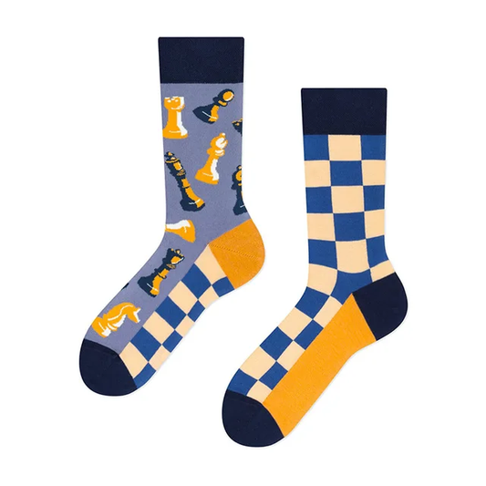 A pair of blue and yellow mismatched crew socks with one featuring a checkerboard chess board pattern and the other with chess pawns.